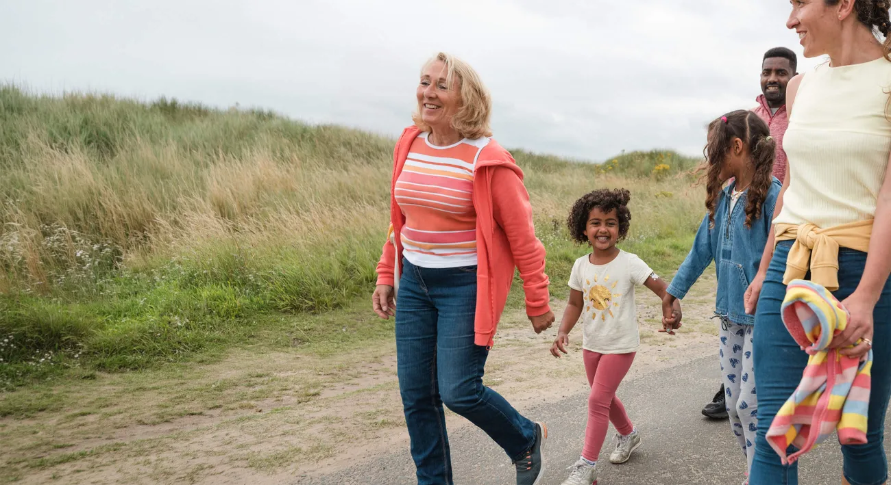 A smiling woman walking with children and a teen